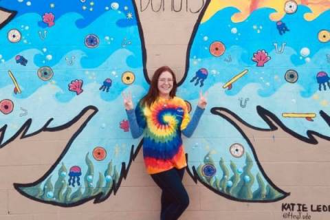 Woman standing in front of wall mural of wings