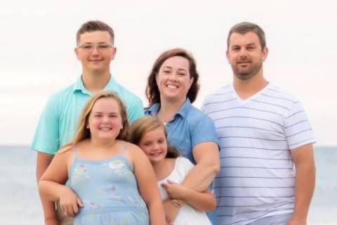 Woman and Man posing with 3 children at beach